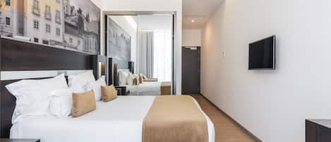 A modern hotel room with a large bed, a flat-screen TV, and a cityscape mural on the wall.