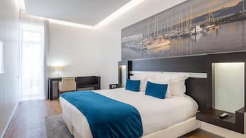 A modern hotel room with a large bed, a desk, and a view of a marina.