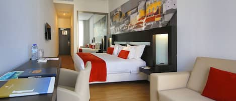 Una habitación de hotel con cama, escritorio, silla, sofá y un espejo grande.