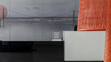Un interior moderno con un gran ventanal con vistas a un puente, un mostrador de recepción blanco y un sofá azul.