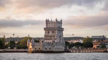 A historic castle with multiple towers, situated by a waterfront.