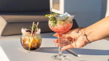 A hand holding a cocktail glass with a straw, a menu card labeled "JUPITER" on a table.
