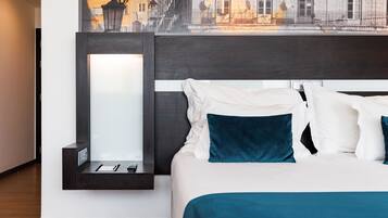 A modern hotel room with a neatly made bed, a bedside table with a lamp, and a view of a building through a window.