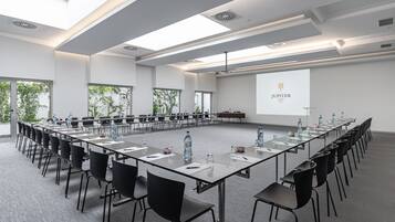 A conference room with a long table, chairs, and a projector screen displaying "JUPITER LUSSONA".