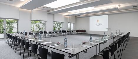 Una sala de conferencias con una larga mesa, sillas y una pantalla proyectora que muestra