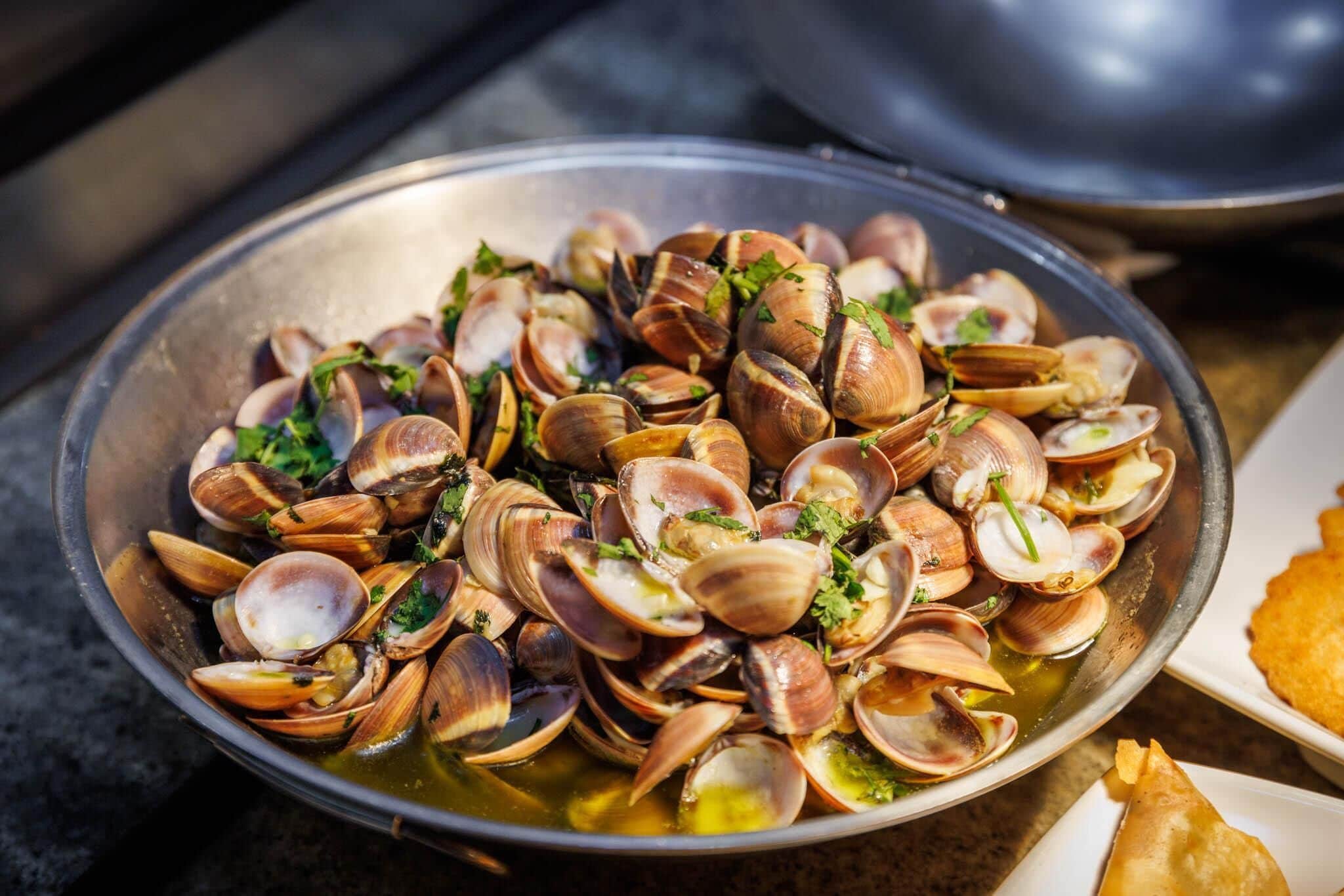 A bowl of clams garnished with herbs.
