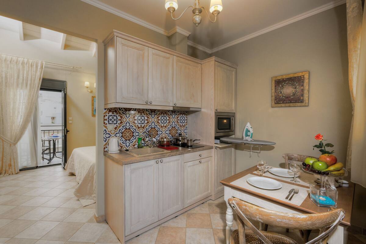 Una cocina compacta con armarios de madera, salpicadero de azulejos y comedor con mesa para dos.