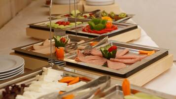 A buffet with various food items including meats, cheeses, and vegetables.