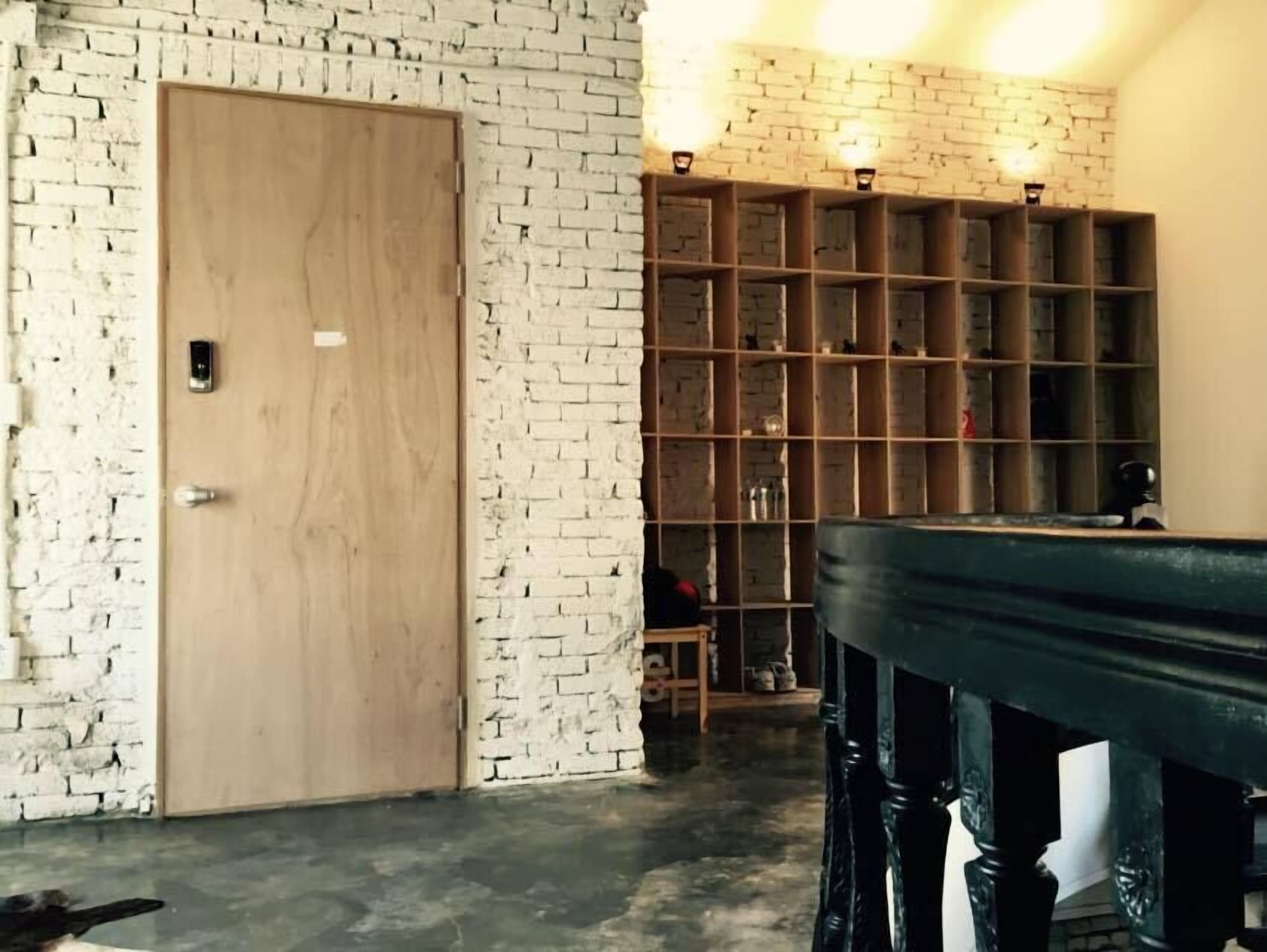 Une pièce avec une porte en bois, un mur en briques et une étagère contenant divers objets.