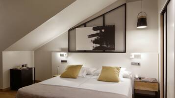 A modern bedroom with a large bed, two bedside tables, a wall-mounted artwork, and a ceiling light fixture.