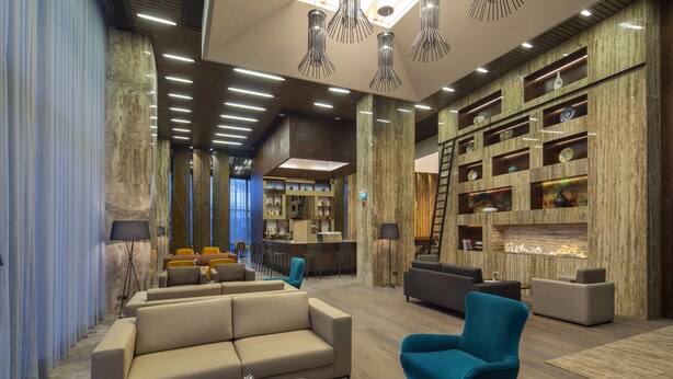 A modern living room with a sofa, armchairs, a coffee table, and a fireplace. - Hilton Garden Inn Istanbul Airport (Istanbul)