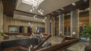 A modern lobby with a central water feature, glass railings, and a staircase. - Hilton Garden Inn Istanbul Airport (Istanbul)