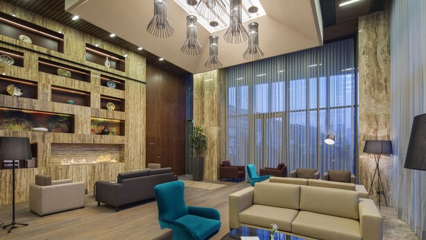 A modern lobby with a fireplace, sofas, and a large window with curtains. - Hilton Garden Inn Istanbul Airport (Istanbul)