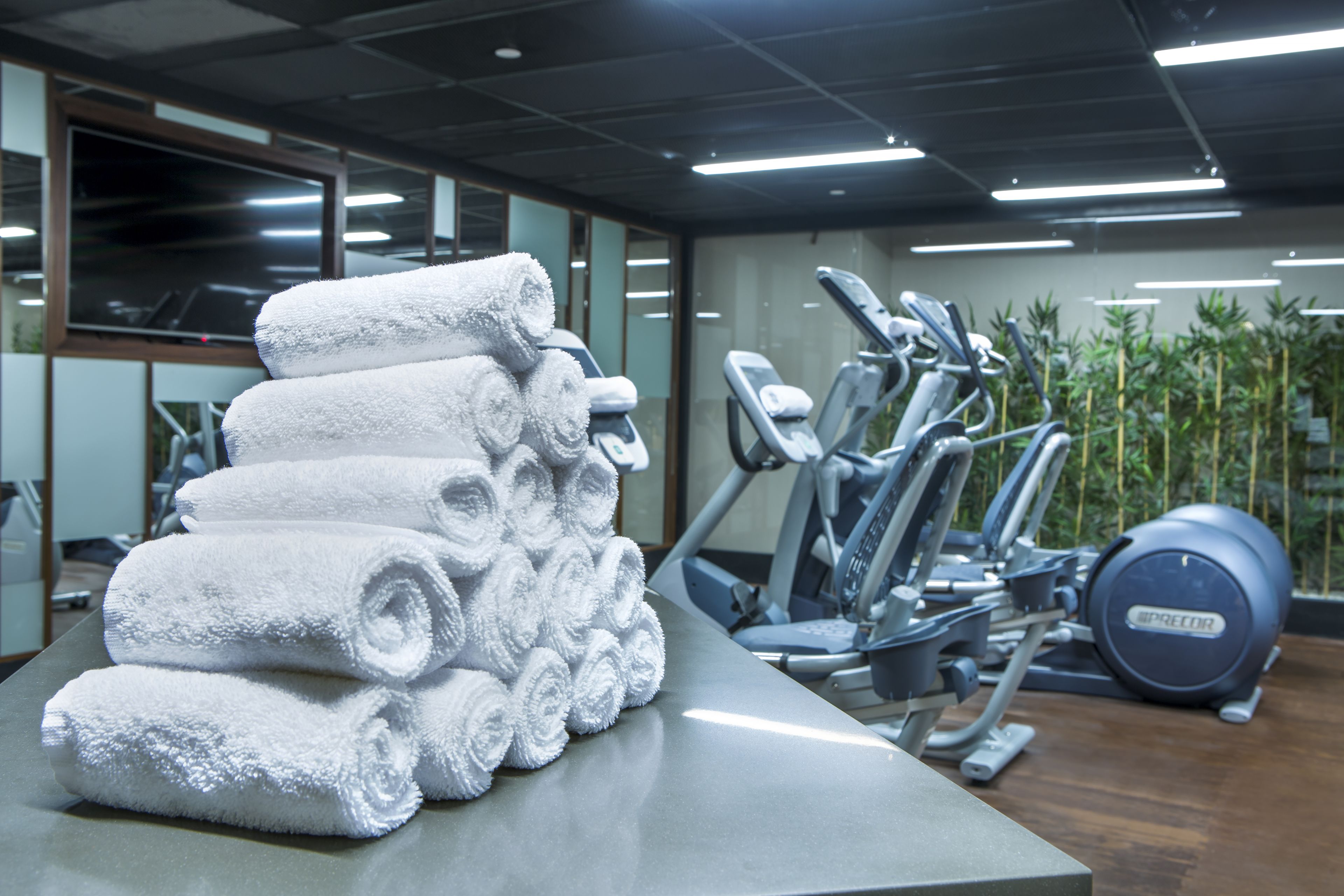 A gym with exercise equipment and a stack of white towels on a table.