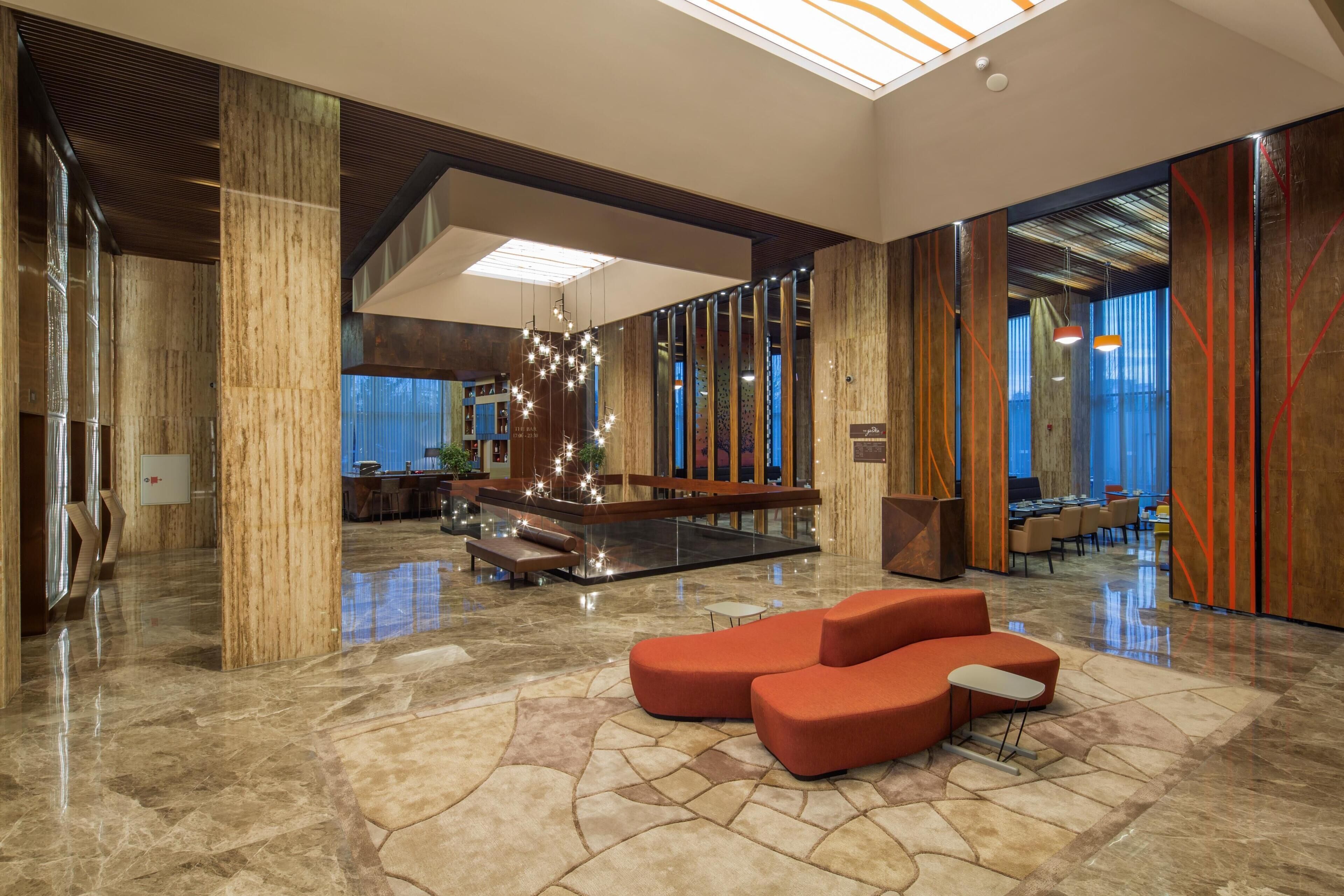 A spacious lobby with a central seating area, a reception desk, and a large window providing a view of the interior.