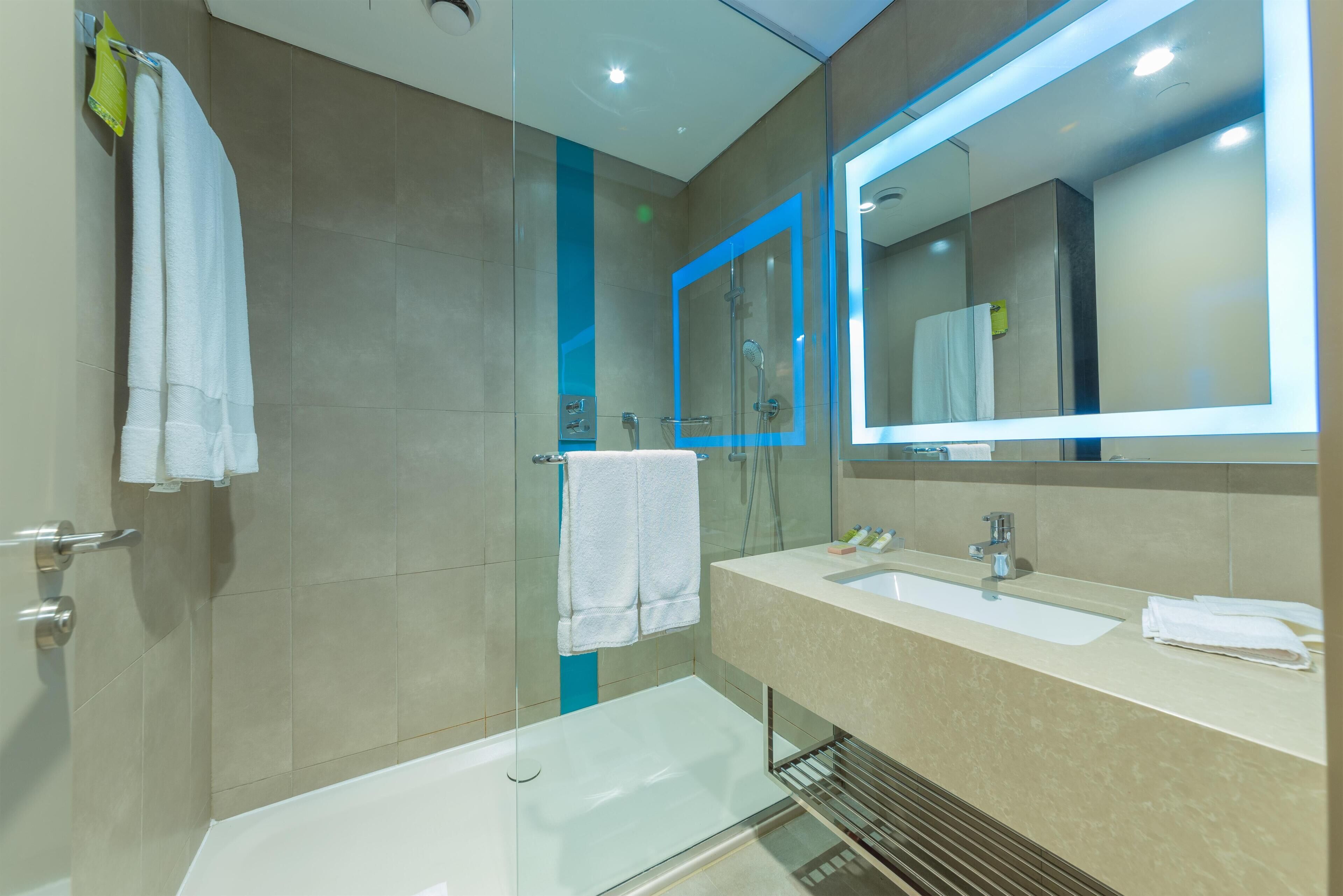 A modern bathroom with a glass-enclosed shower, a bathtub, and a vanity with a mirror.
