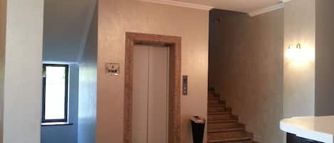 Un pasillo con una escalera, una puerta que indica "primer piso" y un cubo de basura.