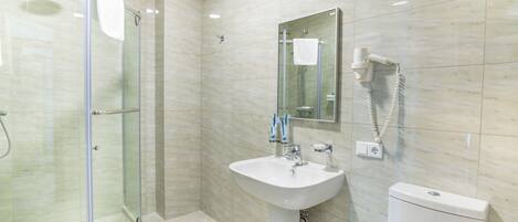A modern bathroom with a glass-enclosed shower, a white sink, and a toilet.