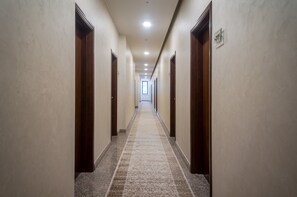 A long, narrow hallway with wooden doors on both sides and a patterned carpet.