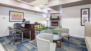A hotel lobby with a reception desk, green seating area, fireplace, and a framed abstract art piece on the wall. - Holiday Inn Express & Suites Glasgow by IHG (Glasgow)