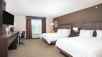 Quarto de hotel com duas camas, uma escrivaninha, uma cadeira, uma televisão e uma janela com cortinas.