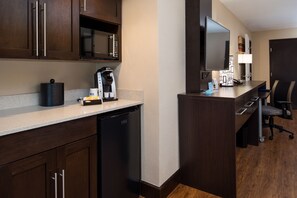 Una cocina moderna con armarios de madera oscura, un microondas integrado, una cafetera y un lavavajillas.