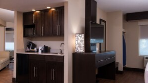A modern kitchen with dark wood cabinets, a built-in microwave, and a coffee maker. - Holiday Inn Express & Suites San Antonio Medical-Six Flags by IHG (San Antonio)