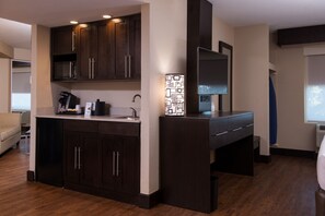 Una cocina moderna con armarios de madera oscura, microondas integrado y cafetera.