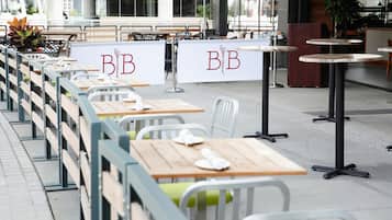 Outdoor seating with tables and chairs, a sign with 'B&B' lettering, and a building in the background.