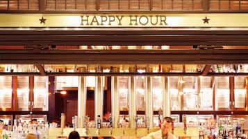 A bar named Barrel & Bushel with a 'Happy Hour' sign, bar stools, and a bartender.