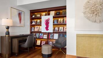 Una biblioteca moderna con estanterías, un escritorio, una silla y un elemento decorativo en la pared.