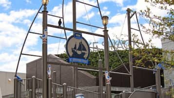 A playground with a ship-themed play structure, a blue mascot figure, and a sign indicating a discovery center.
