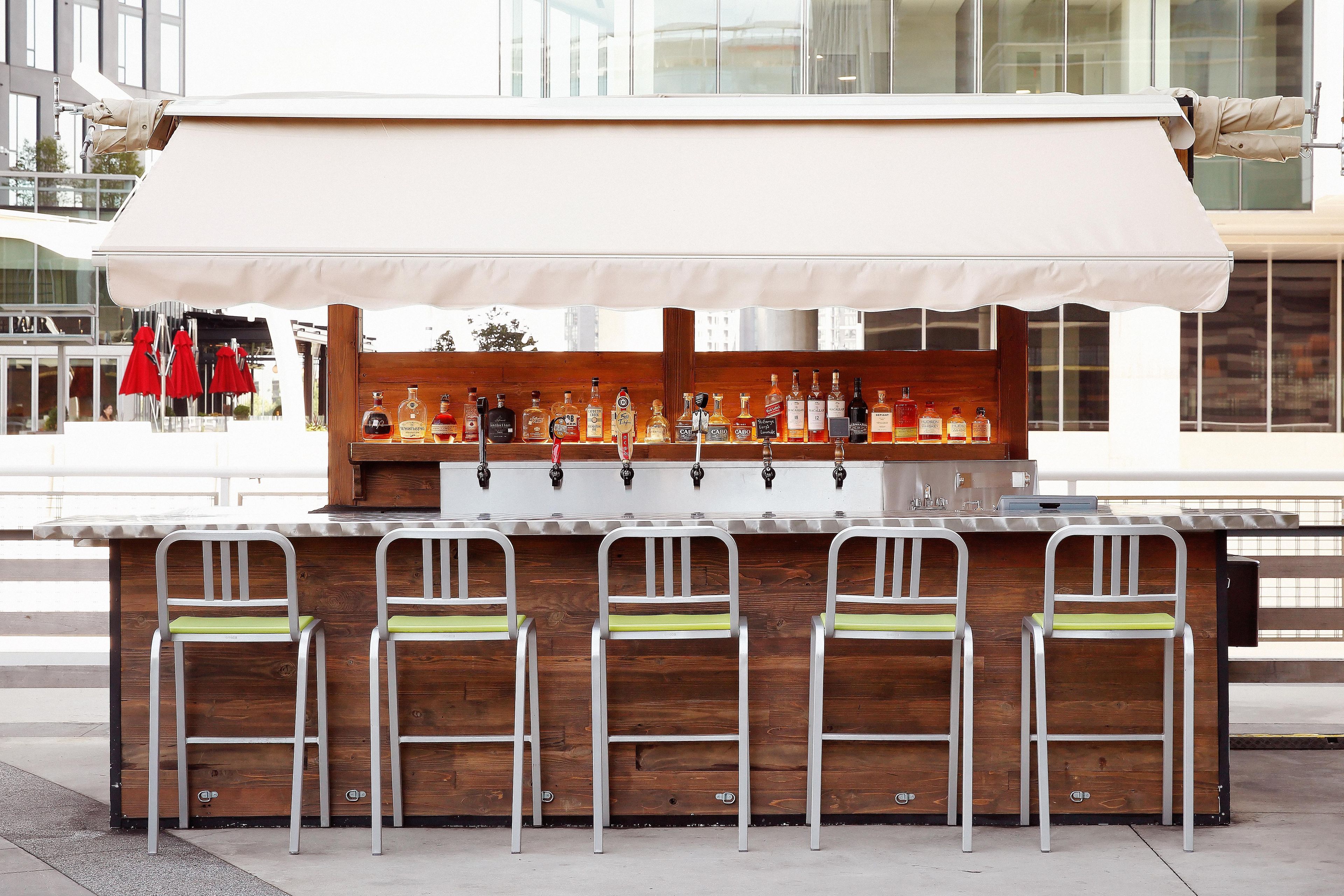 A bar with a white canopy, multiple taps, and bar stools with green cushions.