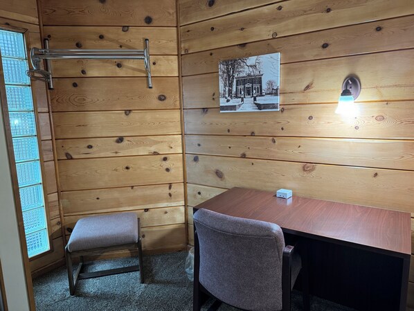 Ein Zimmer mit Holzwänden, einer Bank, einem Tisch, einem Bild an der Wand und einer Leuchte.