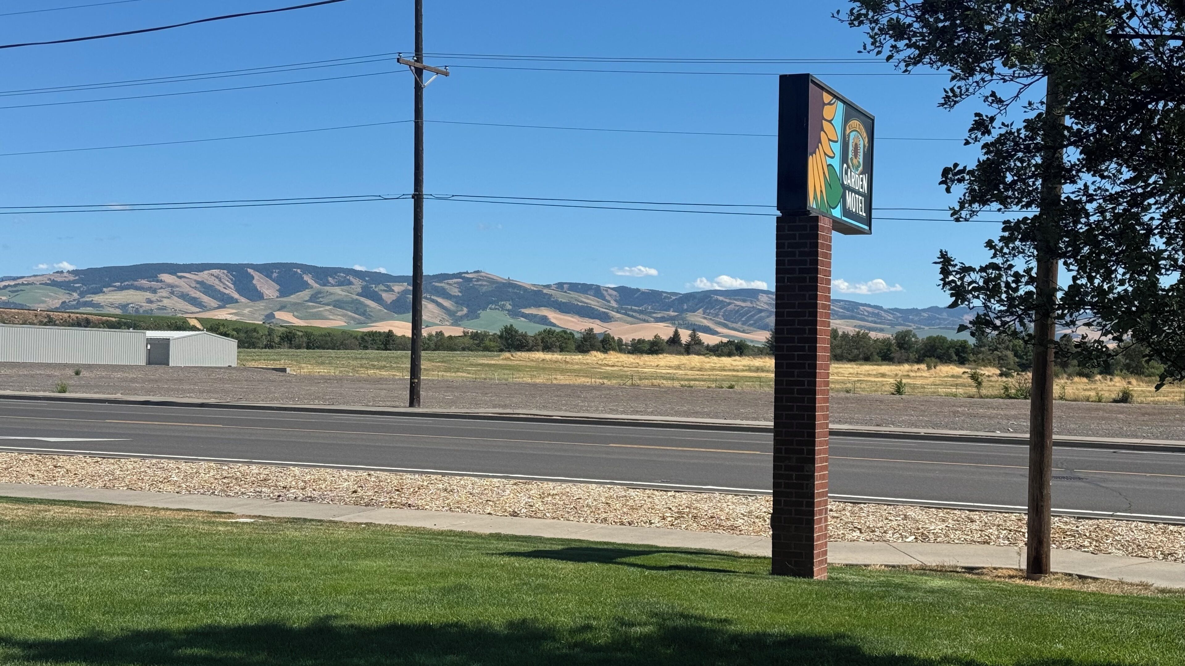 Una carretera con un pilar de ladrillo y un letrero que indica el Motel Garden.