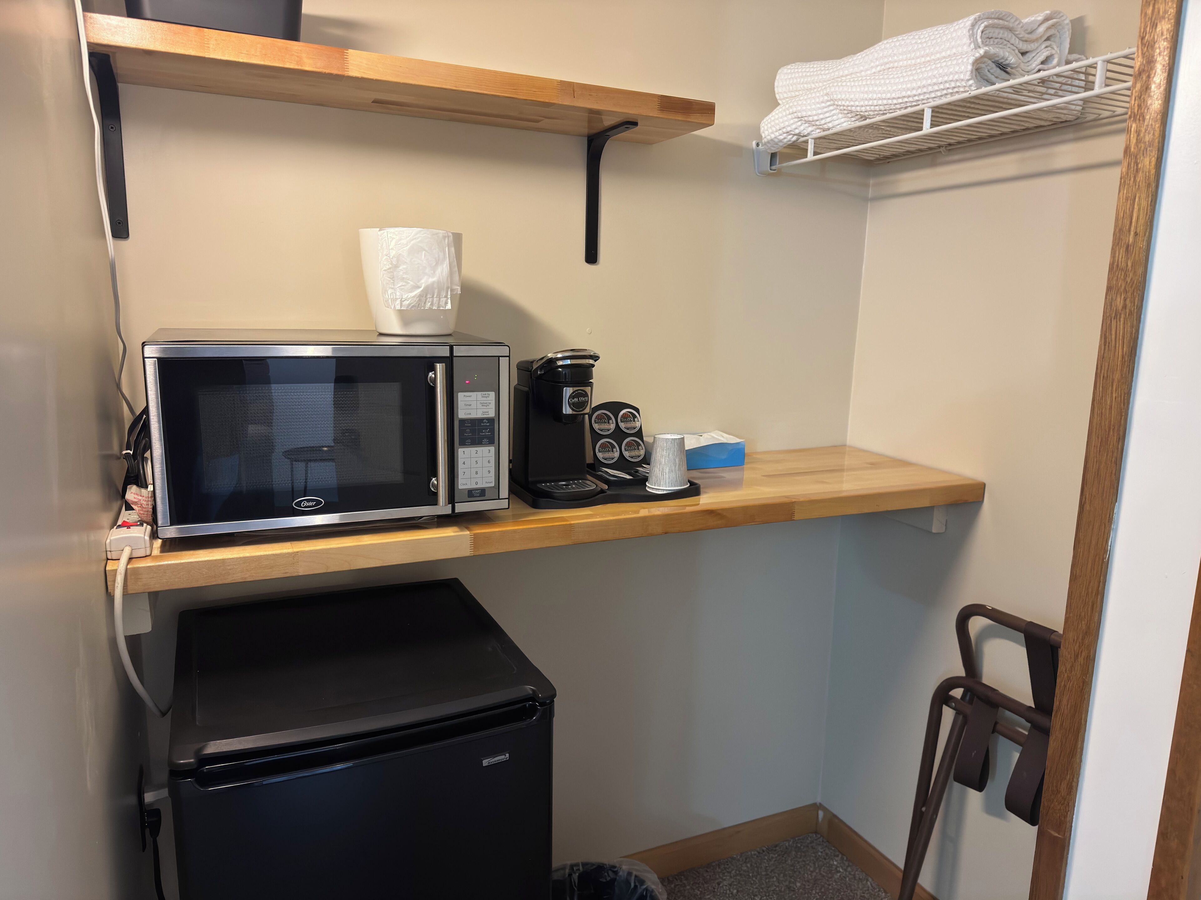 A compact kitchenette with a microwave, coffee maker, and a small refrigerator.