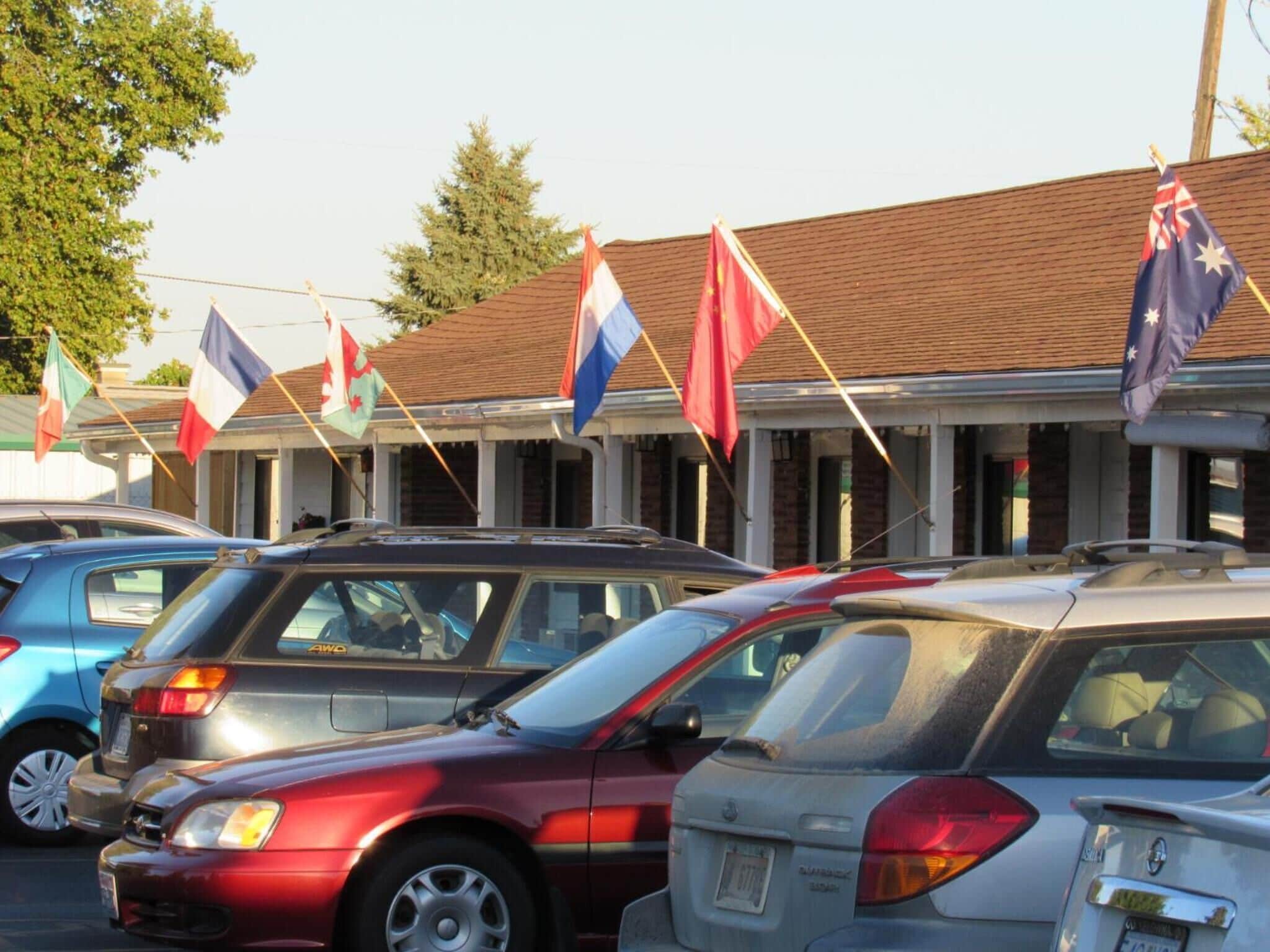 Une rangée de voitures garées devant un immeuble orné de plusieurs drapeaux.