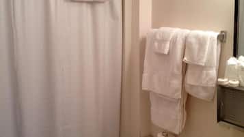 A bathroom with a shower curtain, a toilet, a sink, and a mirror.
