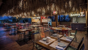 An outdoor restaurant with wooden tables and chairs, hanging decorations, and a bar area. - Stella Palace Aqua Park Resort (Hersonissos)