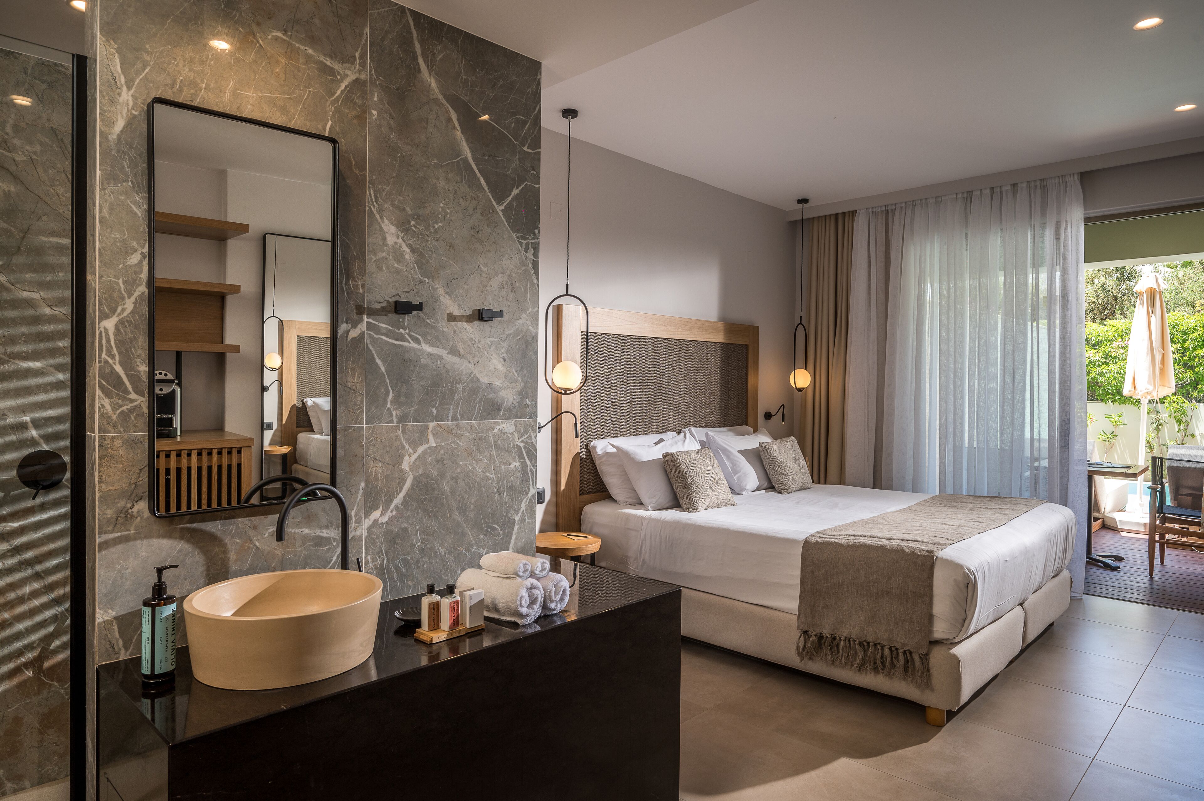 A modern hotel room with a marble bathroom, a large bed, and a view of the outdoors.