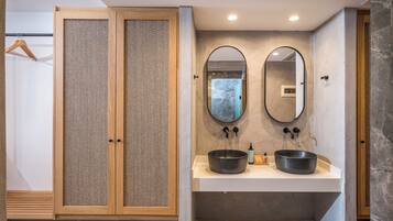 Un baño moderno con un armario de madera, dos espejos redondos y un lavamanos central.
