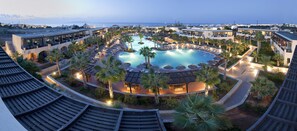 A resort with a central swimming pool, multiple guest rooms, and palm trees. - Stella Palace Aqua Park Resort (Hersonissos)