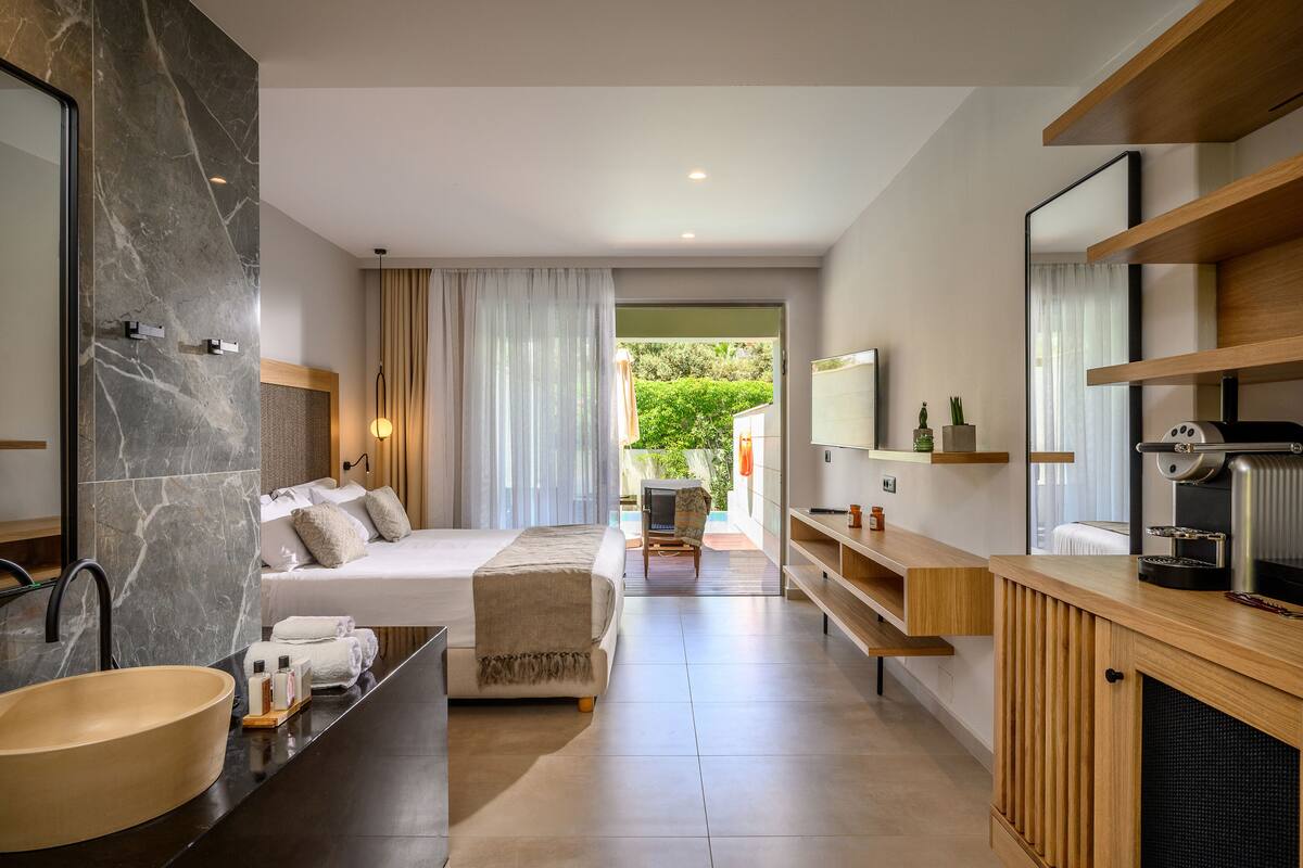 Een moderne hotelkamer met een groot bed, een badkamer met een marmeren wastafel en een televisie.