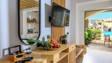 Un baño moderno con tocador de madera, un espejo grande y un televisor de pantalla plana montado encima.
