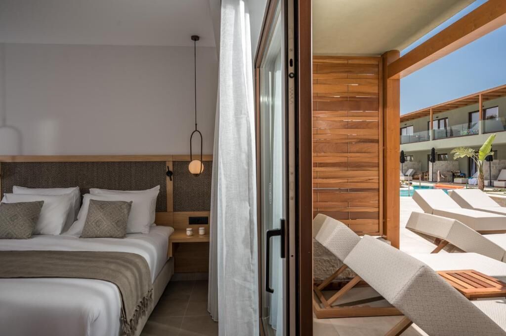 Una habitación de hotel moderna con una cama, una mesita de noche y vistas a la zona de la piscina.