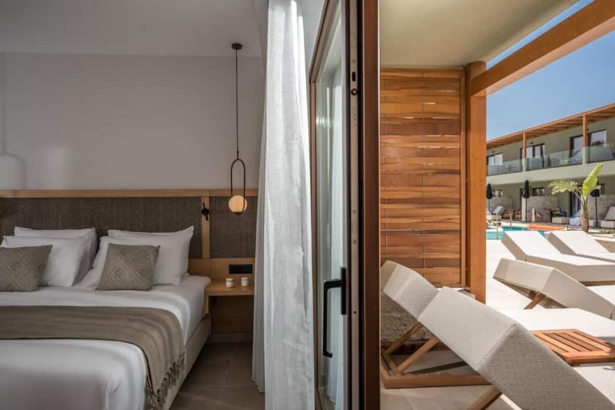 Una habitación de hotel moderna con una cama, una mesita de noche y vistas a la zona de la piscina.