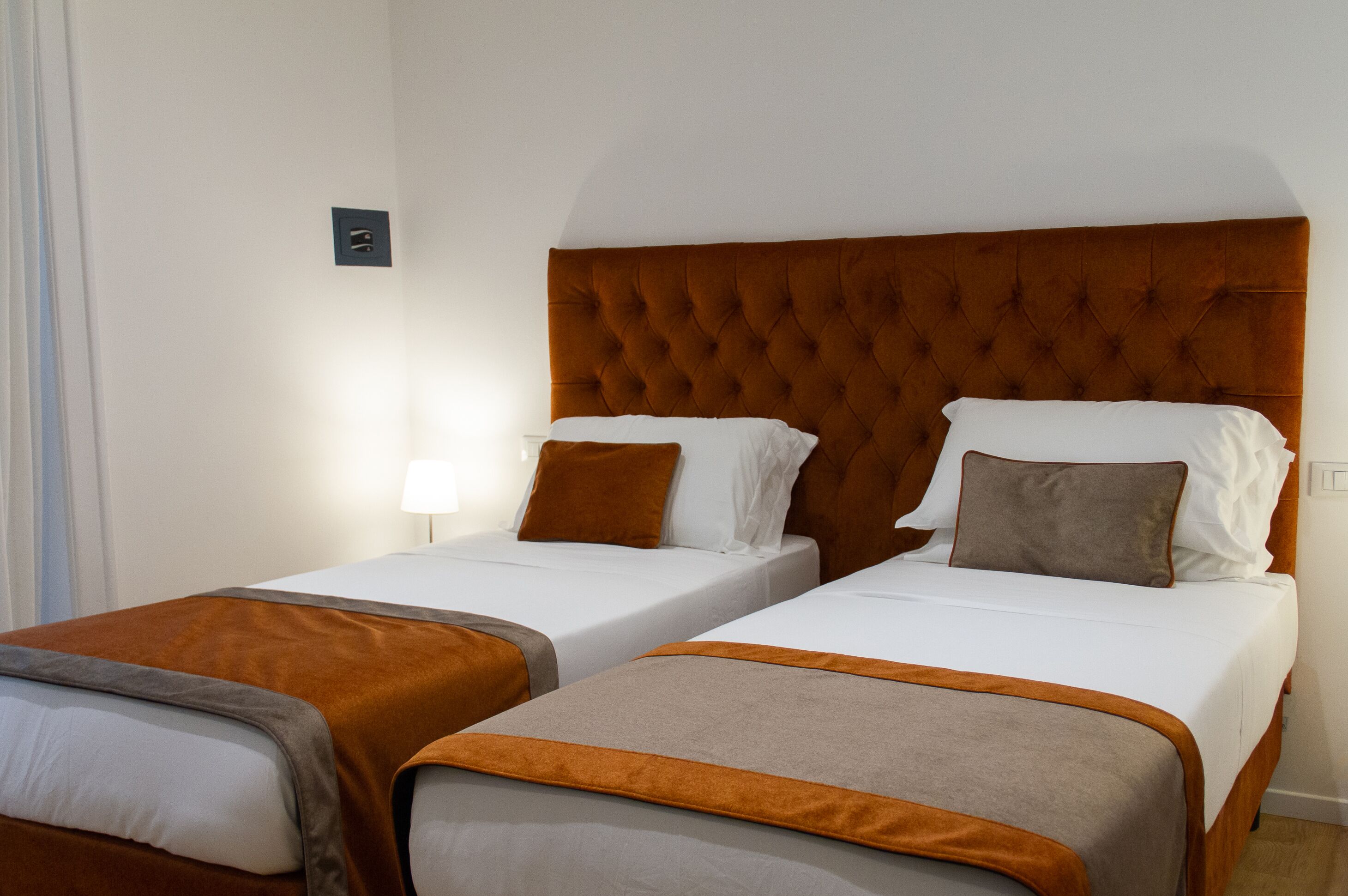 A hotel room with two single beds, each with a brown headboard and white bedding.
