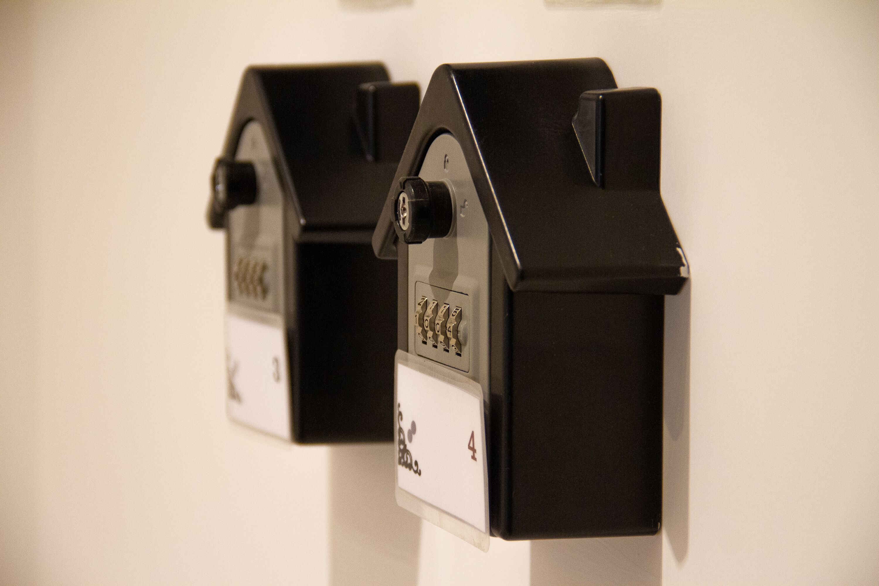 Dos objetos negros con forma de casa, con un teclado y una pantalla, montados en una pared.