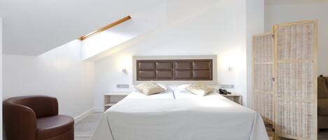Un dormitorio moderno con una cama grande, un sillón de cuero marrón y un separador de madera.
