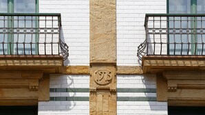 A building facade with white brick walls, green window frames, and a central column with the year '1915' engraved. - Hotel Santa Rosa, Blue Hoteles (Gijon)